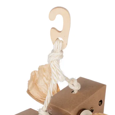 Crochet en bois attaché à une corde blanche, relié à un élément en carton marron avec trous visibles et papier froissé beige.
