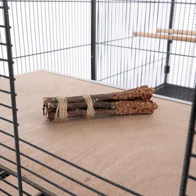 Száraz virágokkal díszített fa rudak, juta kötéllel összekötve, fa felületen, ketrecben elhelyezve.