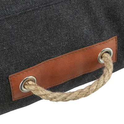 Detailansicht einer schwarzen Stofftasche mit braunem Ledergriff und Seilhenkel durch Metallösen.