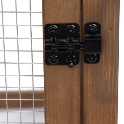 Fermeture en métal noir sur porte en bois avec grillage métallique à mailles carrées, vue rapprochée du système de verrouillage.