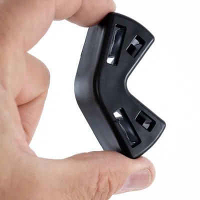 Pièce en plastique noire de forme angulaire avec quatre ouvertures rectangulaires, tenue entre deux doigts.