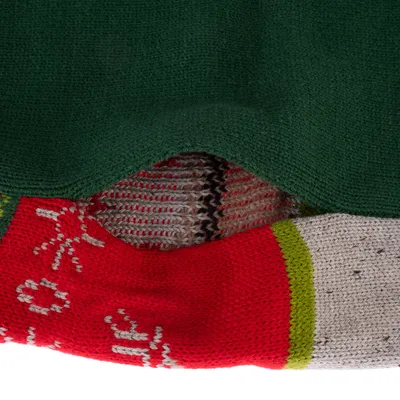 Nahaufnahme von gestricktem Material in Grün, Rot mit Schneeflockenmuster und Weiss mit grünem Streifen.