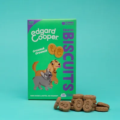 Edgard Cooper Bravo Biscuits, pomme myrtille. 130 biscuits, sans sucre ajouté, empreinte carbone de 1,5 kg. Emballage avec illustration de chien et forme de biscuit.