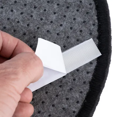 Detailní záběr na ruku otevírající suchý zip šedého, puntíkovaného textilního materiálu.