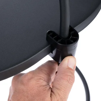 Detailní záběr ruky, která připevňuje kabel do černého držáku na kulatém objektu.