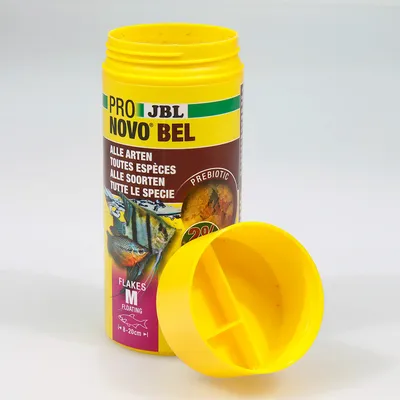Boîte ouverte de JBL Pro Novo Bel, aliment pour poissons, texte visible : toutes espèces, flakes M floating, prébiotic, 8–20 cm. Image de poissons sur l’étiquette.