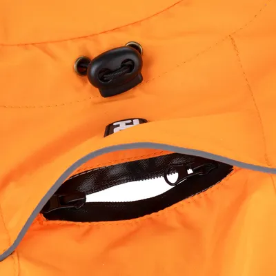 Détail d’un vêtement orange en tissu avec fermeture éclair noire, cordon de serrage noir et liseré gris réfléchissant. Étiquette visible avec texte partiel « HI ».