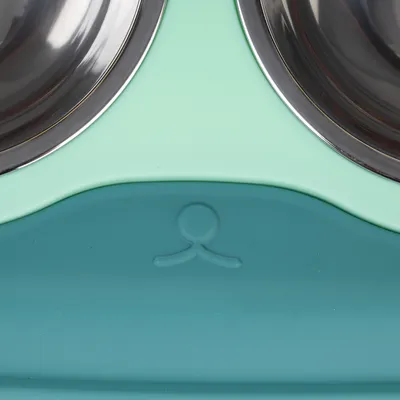 Double bowl made of stainless steel with mint green and turquoise plastic holder, logo visible in the centre.