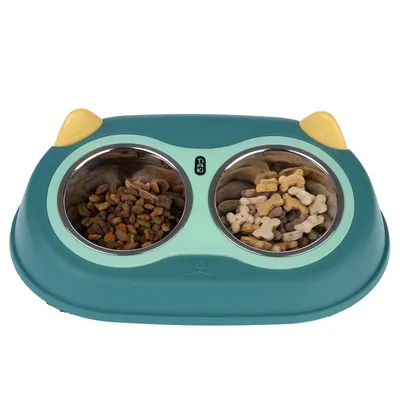 Double bowl in green with yellow accents, brand Taki. Left side filled with dry food, right side with dog bone treats.