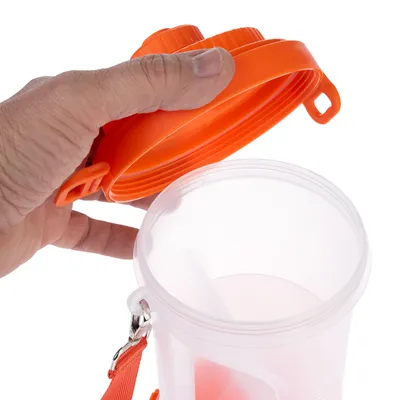 Transparenter Behälter mit orangefarbenem Deckel und Tragegurt, geöffnet und von einer Hand gehalten.