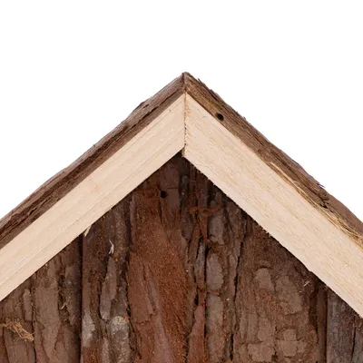 Närbild av ett trähus med naturlig barkstruktur och spetsigt tak av ljust trä.