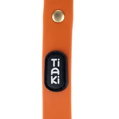 Tiaki-logo op oranje product met goudkleurige knop.