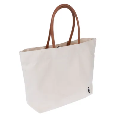 Bolsa de tela beige con asas marrones y pequeña etiqueta negra con el logo en la parte inferior derecha.