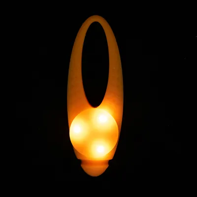 Яркая оранжевая игрушка с тремя световыми точками, подходит для темных помещений.