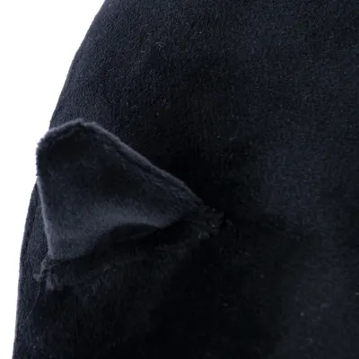 Közelkép fekete textil anyagról, kis háromszög alakú, fülre emlékeztető formával.