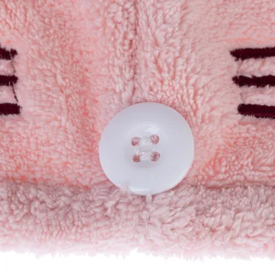 Close-up van roze pluchemateriaal met witte knoop en geborduurde donkerrode lijnen.
