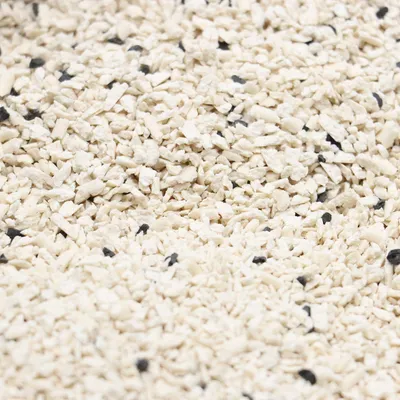 Vue rapprochée de granulés blancs et noirs, texture fine, sans marque ni texte visible. Convient pour illustrer la consistance d’une litière ou d’un substrat en vrac.