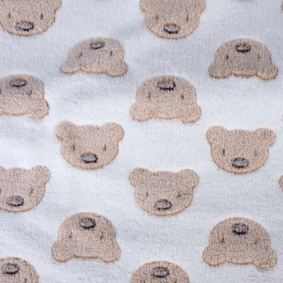 Närbild av ett vitt tyg med upprepat björnhuvudmönster i beige och brunt.