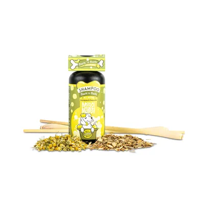 Shampoo Bark'n Bath mit Lemongrass und Kamille, All Natural, Flasche mit gelbem Etikett, umgeben von Kamillenblüten und Holzstücken.