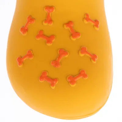 Juguete para perro amarillo con patrones de huesos naranjas en la superficie.