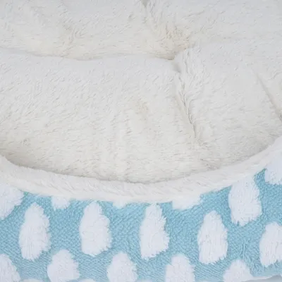 Nahaufnahme eines weissen, flauschigen Innenmaterials und eines blauen Aussenbezugs mit Wolkenmuster. Geeignet für Haustierbetten oder Liegeflächen.