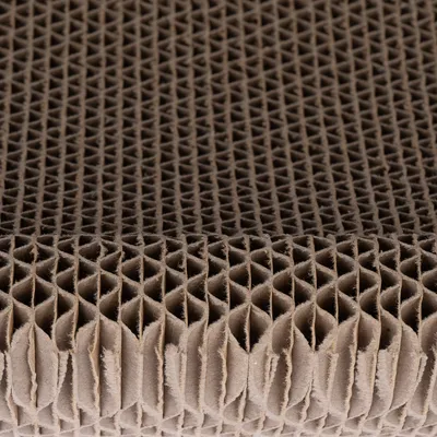 Gros plan sur une surface en carton ondulé, structure alvéolée visible. Matériau utilisé pour griffoirs ou accessoires pour animaux.