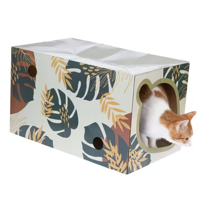 Kartonhaus mit tropischem Blätterdesign und katzenförmigem Eingang, aus dem eine rot-weisse Katze herausschaut.