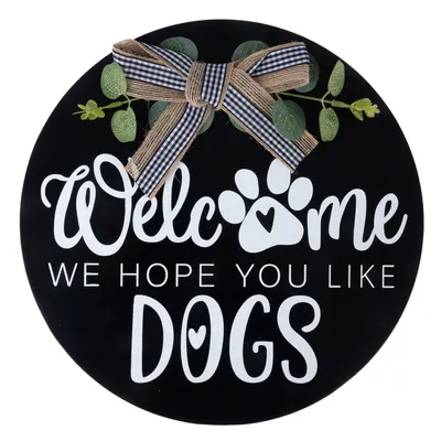 Rundes Schild mit Text: 'Welcome, we hope you like dogs', verziert mit Schleife und grünen Blättern.