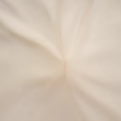 Gros plan sur un tissu beige avec couture centrale visible, matière textile lisse.