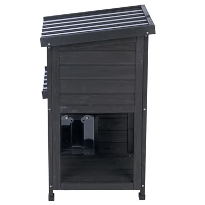 Schwarzes Holzhaus mit schrägem Dach und zwei transparenten Klappen an der Vorderseite.