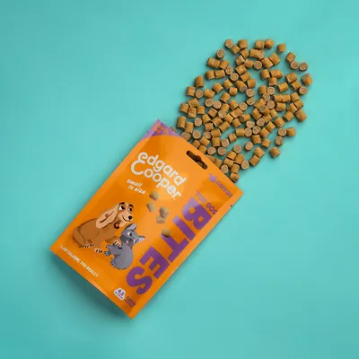 Edgard Cooper Top Dog BITES, small in size, kip. Zak met ronde hondensnacks, oranje verpakking met cartoonhond en -kat. Tekst: low calorie, 125 really, grain free.