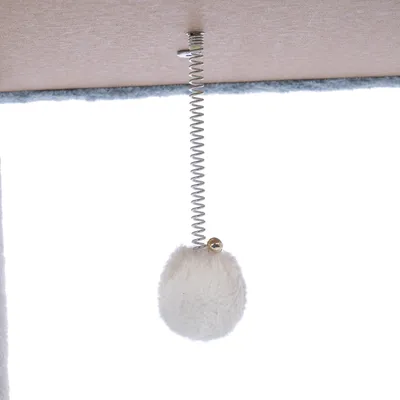 Boule en peluche blanche suspendue à un ressort métallique fixé sous une surface, jouet pour arbre à chat ou griffoir.