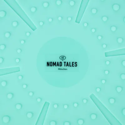Nomad Tales München. Название бренда на мятно-зеленом фоне с текстурированными точками и линиями.