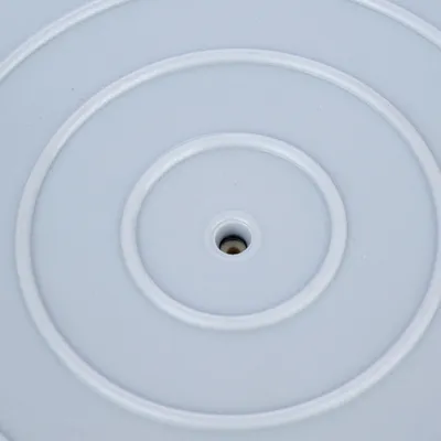 Primo piano di una superficie in plastica grigia con cerchi concentrici e un foro centrale.
