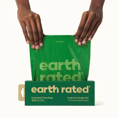 Earth Rated unscented dog waste bags, 300 pieces, green packaging with bag dispenser. Hands pull a bag from the box.