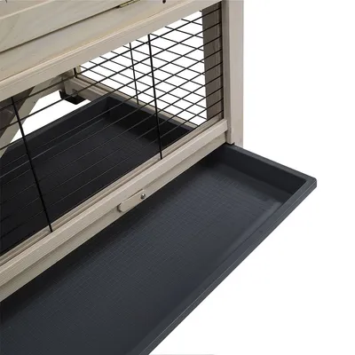 Dettaglio di una gabbia per piccoli animali con struttura in legno, griglia metallica nera e vassoio estraibile in plastica nera alla base.