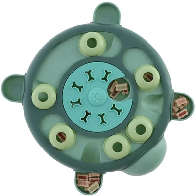 Jouet interactif rond en plastique vert avec compartiments contenant des friandises en forme d’os visibles, motif pattes et os au centre.