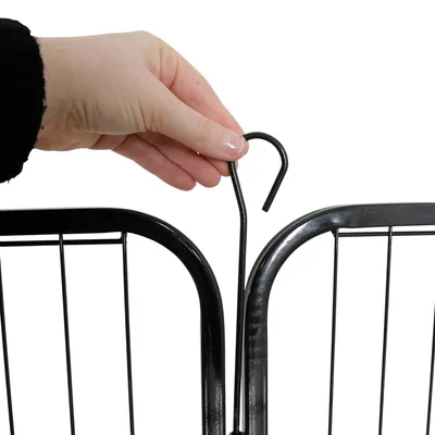 Hand zeigt, wie ein schwarzer Metallhaken zwei Gitterelemente verbindet.