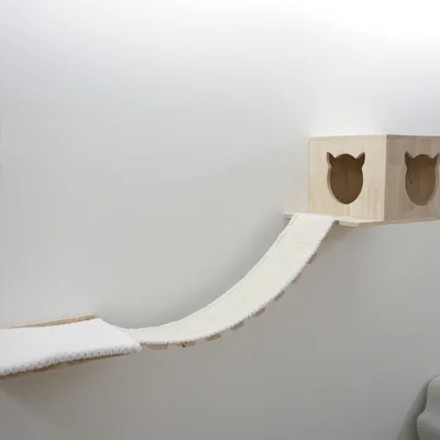 Wooden cat house with two cat-shaped entrances, connected by a white fabric ramp. Suitable for wall mounting.