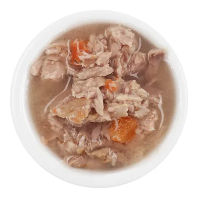 Närbild av våtfoder i en vit skål, bestående av köttbitar och morötter i buljong.
