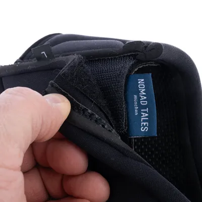 Nahaufnahme eines schwarzen Stoffmaterials mit Klettverschluss und blauem Etikett 'Nomad Tales München'.