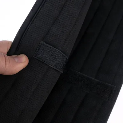 Nahaufnahme eines schwarzen Klettverschlusses an einem Stoffmaterial, gehalten von einer Hand.