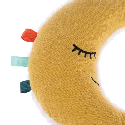 Crescent-shaped yellow fabric toy with embroidered closed eyes and colourful loops in red, green and turquoise on the side.
