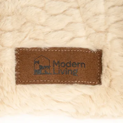 Modern Living. Logo auf braunem Stoffetikett, angenäht an cremefarbenem Kunstfell. Modern Living. Logo auf braunem Stoffetikett, angenäht an cremefarbenem Kunstfell.