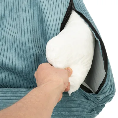 Mano che mostra l’imbottitura bianca rimovibile da una fodera turchese con cerniera.