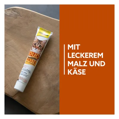 GimCat Duo Paste Anti-Hairball mit leckerem Malz und Käse, Tube auf Holzuntergrund.