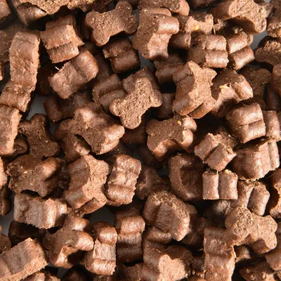 Snack per cani marroni a forma di osso in primo piano. Texture visibile degli snack.