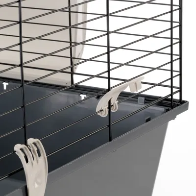 Detailansicht eines grauen Kleintierkäfigs mit schwarzem Gitter und weißen Kunststoffverschlüssen.