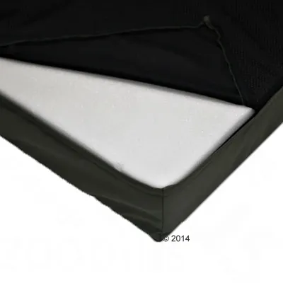 Vue rapprochée d’un matelas avec housse noire partiellement ouverte, montrant un intérieur en mousse blanche. Aucun texte ou marque visible.
