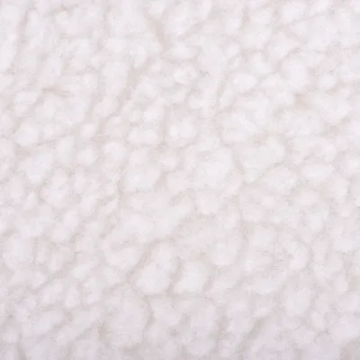 Detail povrchu bílé textilie s chlupatou strukturou, materiál připomíná umělou vlnu nebo fleece